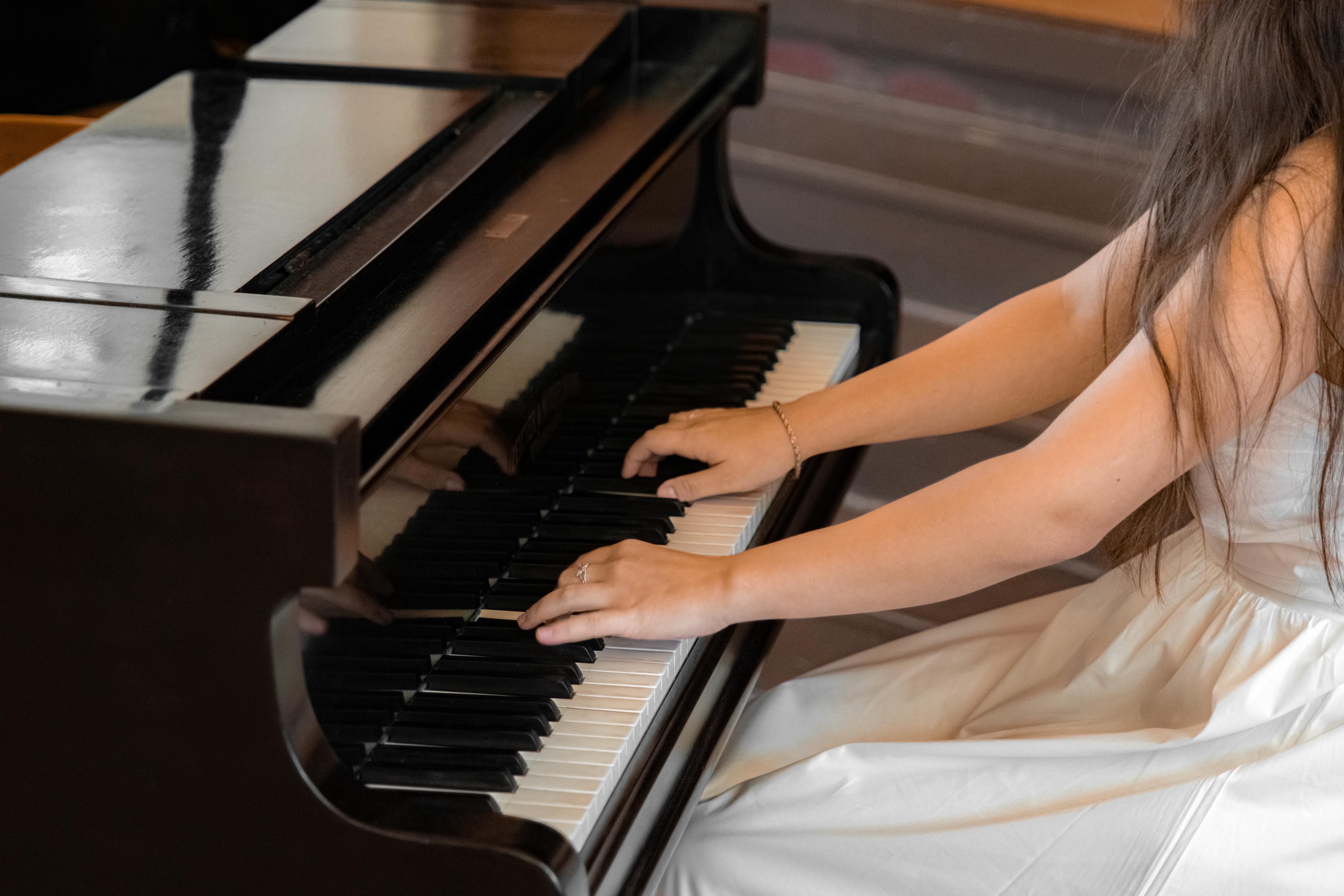 Nahaufnahme von Händen einer Frau in weißem Kleid, die Klavier spielt