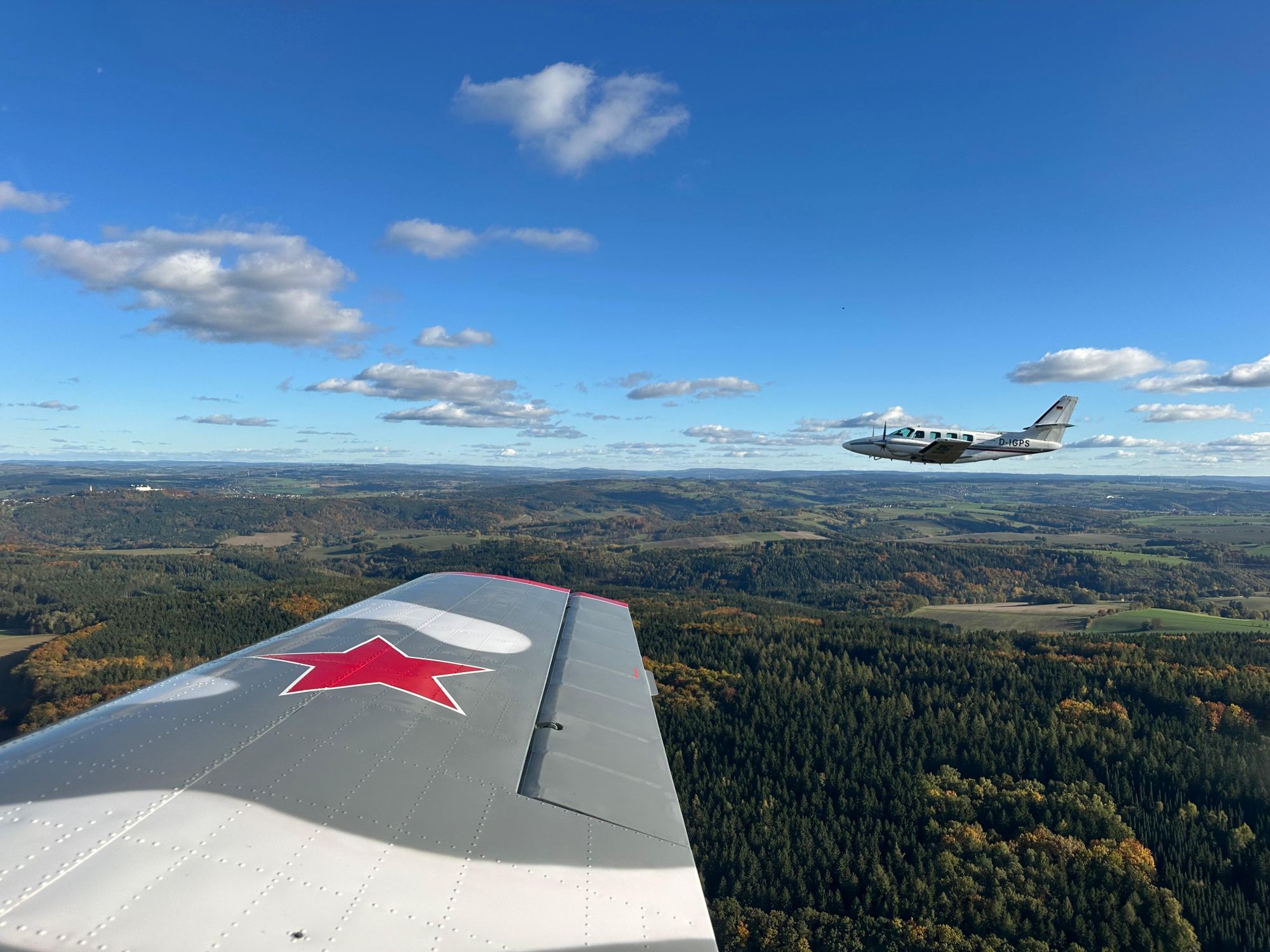Flugzeuge fliegen über grüne Wälder und Hügel bei klarem Him