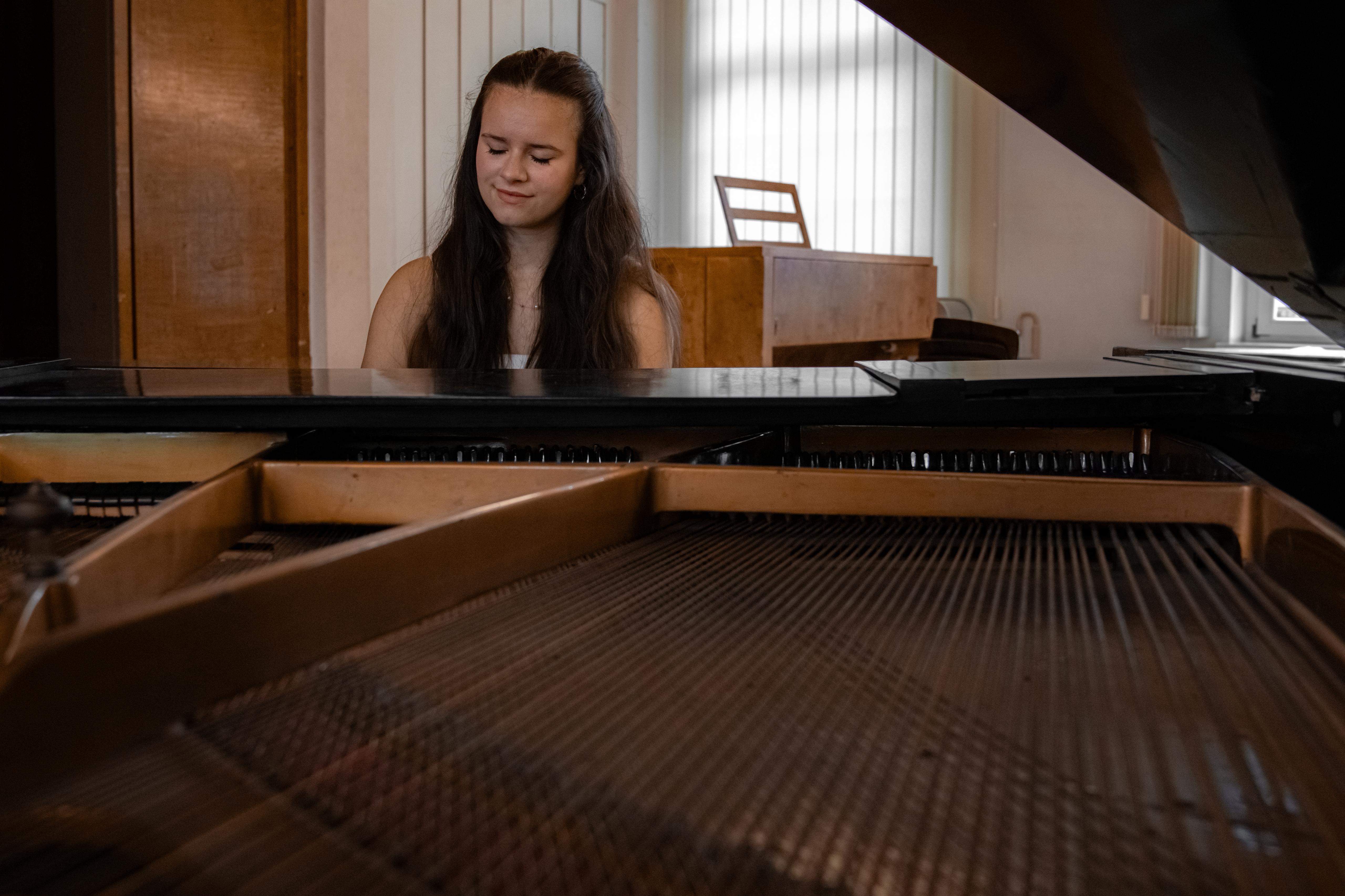 Eine Frau sitzt an einem Flügel und spielt Klavier in einem Musikraum