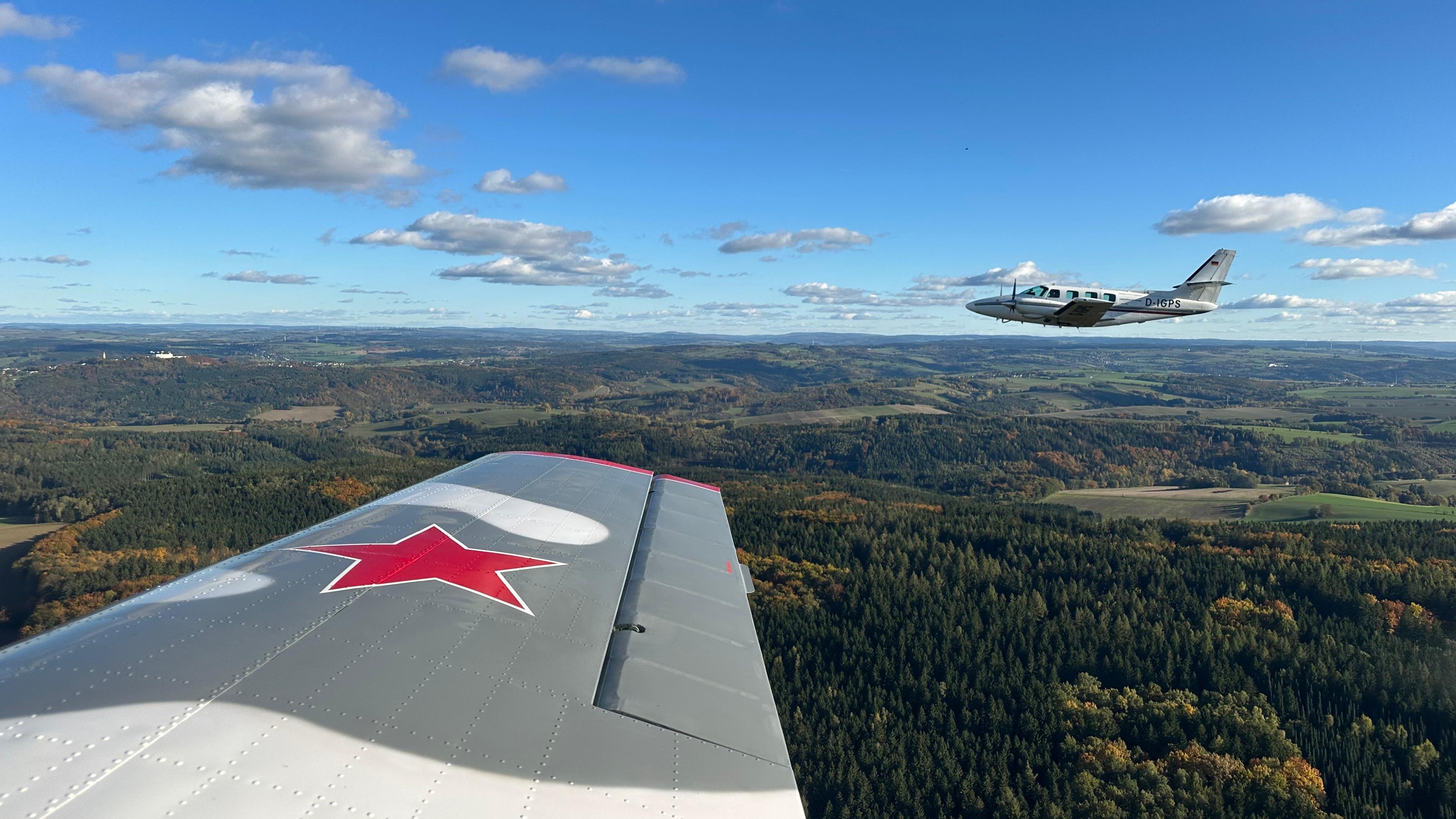 Zwei Flugzeuge fliegen über herbstliche Landschaft mit blaue
